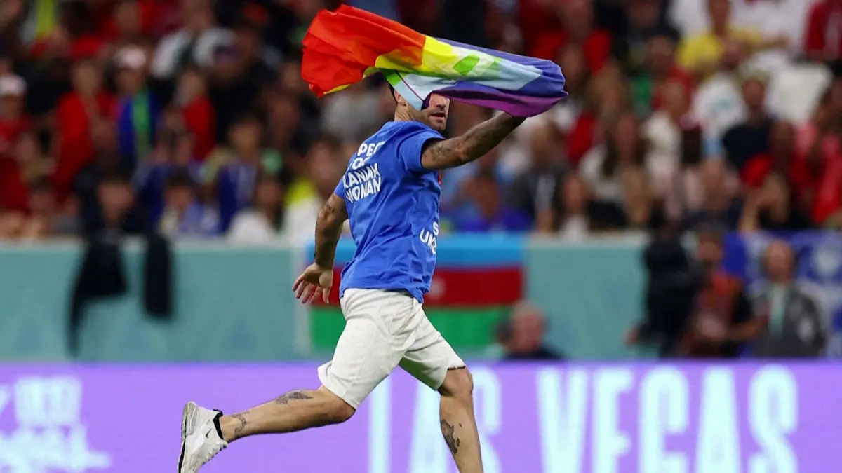 An activist running to the match in Qatar with a rainbow flag
